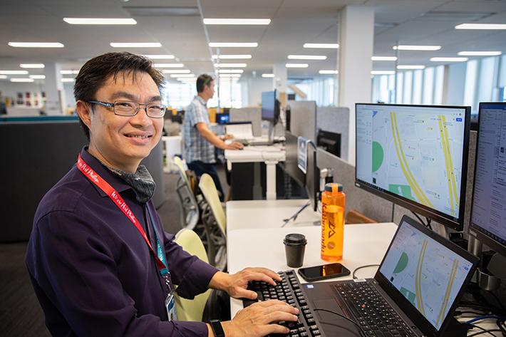Council staff member types at a computer, in the background another staff member works at a stand-up desk